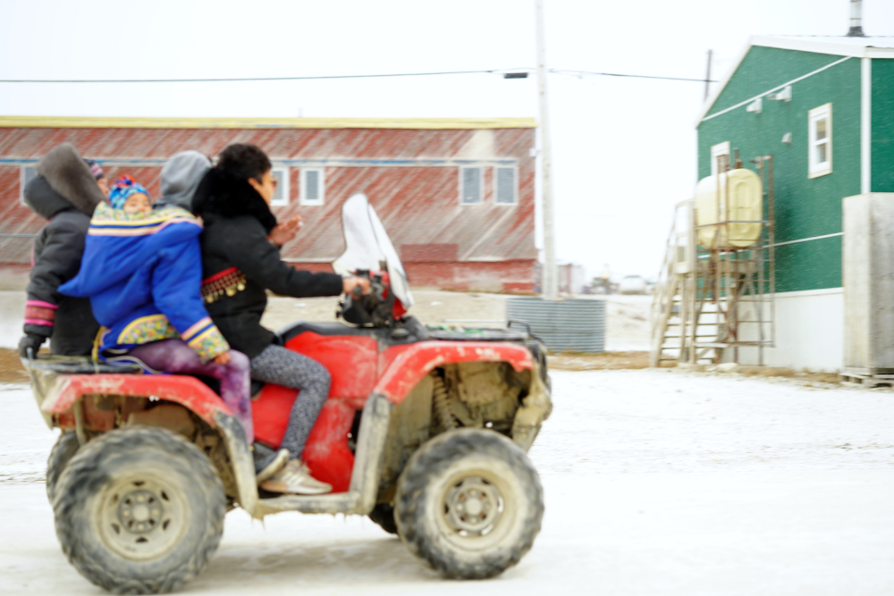 Eine Inuit-Familie: Mutter, Tochter, Säugling 
			und Sohn auf einem der typischen Quads, die den ganzen Tag durch Igloolik kurven.